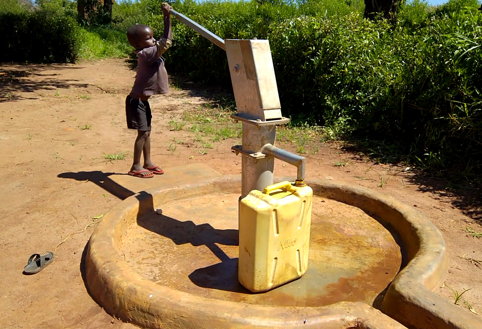 A child pumping water from a borehole BMS World Mission built. 