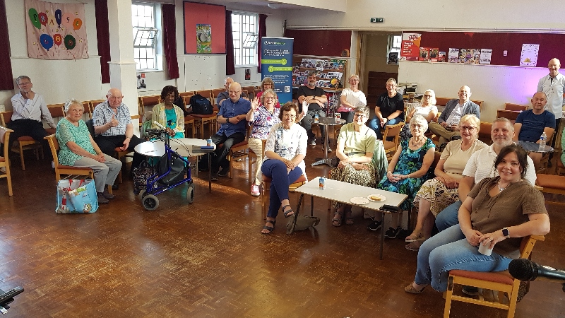 A group of people sat on chairs around tables at Suffolks Baptist Church, Enfield