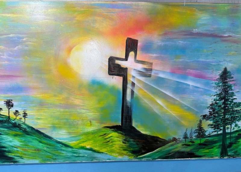 A mural showing the suns rays shining through a cross in the green Lebanese countryside
